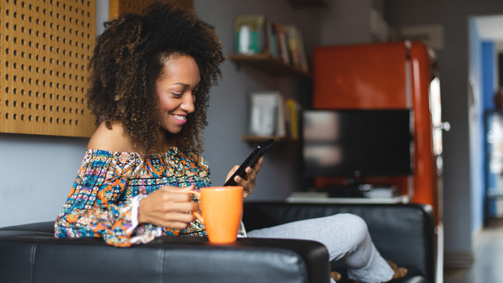 Woman enjoying hot drink on her phone